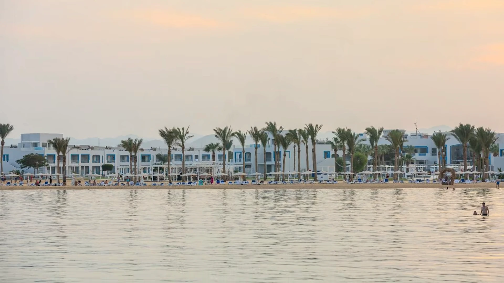 Strand und flache Hotelgebäude vom Wasser aus – Casa Blue Resort
